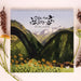 A 2027 wall calendar titled 'Ode to Joy' featuring a watercolor mountain landscape with yellow wildflowers, styled in a flat-lay with pinecones and flowers on a light beige background.