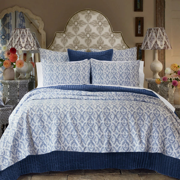 Bedroom with blue and white patterned bedding, pillows, and lamps.