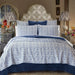 Bedroom with blue and white patterned bedding, pillows, and lamps.