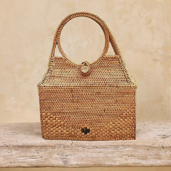 Woven handbag on a wooden surface with a beige background