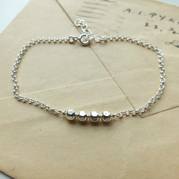 Silver bracelet with small beads on a textured surface