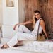 Woman in a white outfit sitting on steps with a wicker bag