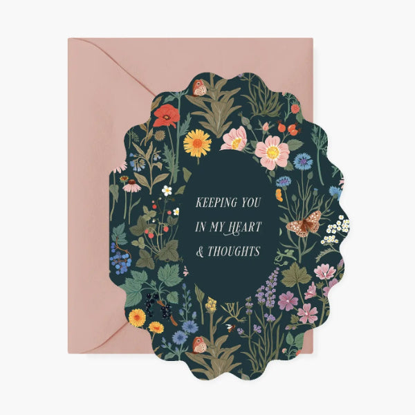 Greeting card with floral design and text 'Keeping you in my heart & thoughts' on a pink envelope.
