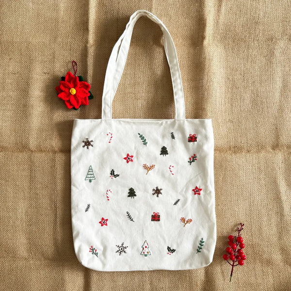 White tote bag with Christmas-themed patterns on a beige fabric background