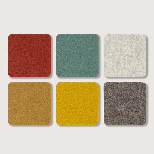 Six square felt-like swatches in different colors arranged in a 2x3 grid on a light gray background: red, teal, off-white, tan, mustard yellow, and dark gray.