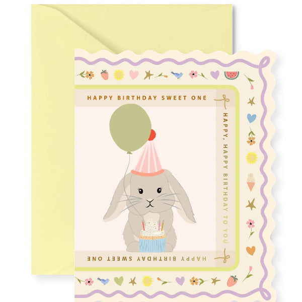 Birthday card with a rabbit holding a balloon and cake, on a yellow envelope.