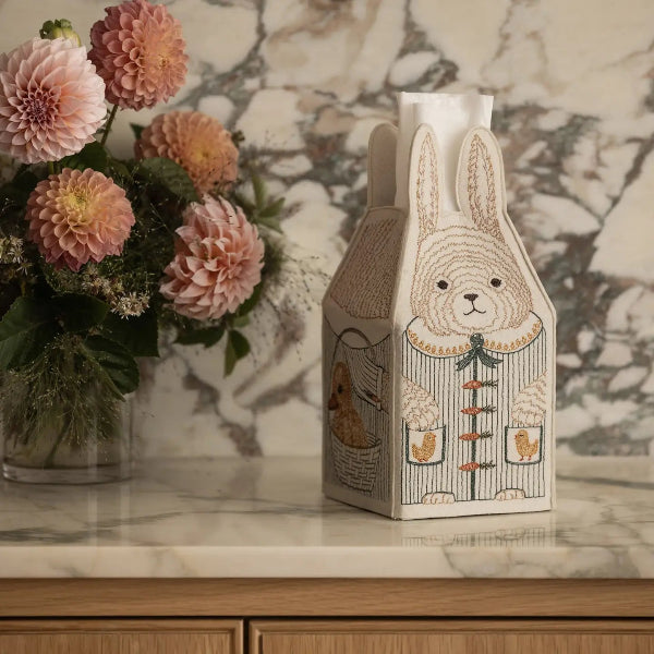 Decorative box with rabbit design on a marble surface with flowers in the background