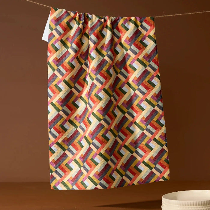 Colorful geometric patterned towel hanging on a line against a brown background