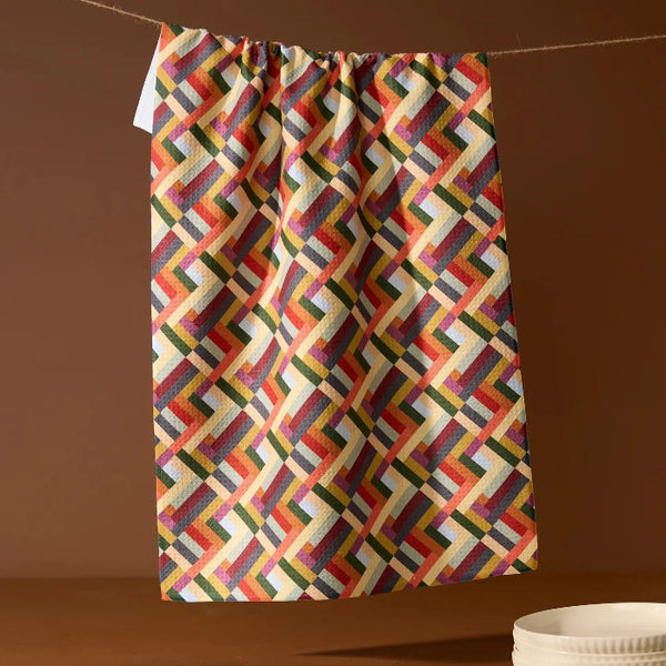 Colorful geometric patterned towel hanging on a line against a brown background