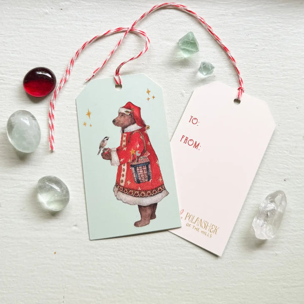 Gift tag with a bear illustration and a card on a light surface with decorative elements.
