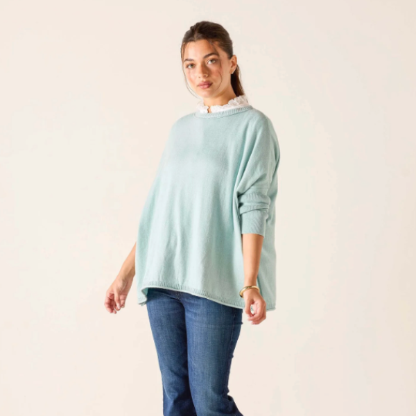 Woman wearing a light blue sweater and jeans on a beige background