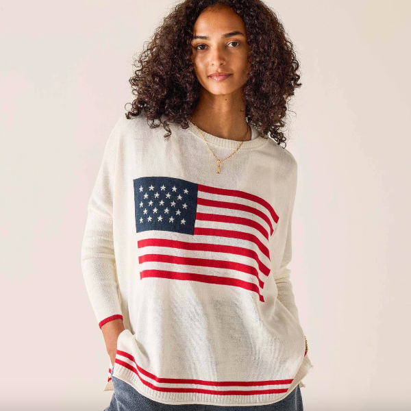 Woman wearing a sweater with an American flag design on a plain background