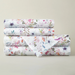 Stack of floral-patterned bed sheets on a light gray background