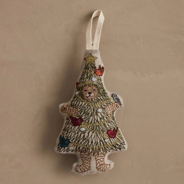 A handmade embroidered Christmas ornament shaped like a tree made from a teddy bear's body, decorated with colorful beads and a gold star, hanging against a textured beige background.