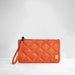 An orange quilted nylon wristlet clutch with a matching wrist strap and a small circular brand patch on the front, set against a clean white studio background.