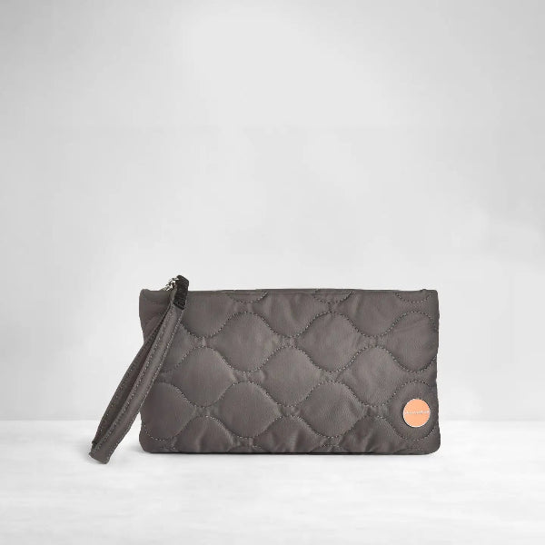 A dark gray quilted clutch bag with a matching wristlet strap and a small circular rose gold accent on the front, set against a clean light gray background.