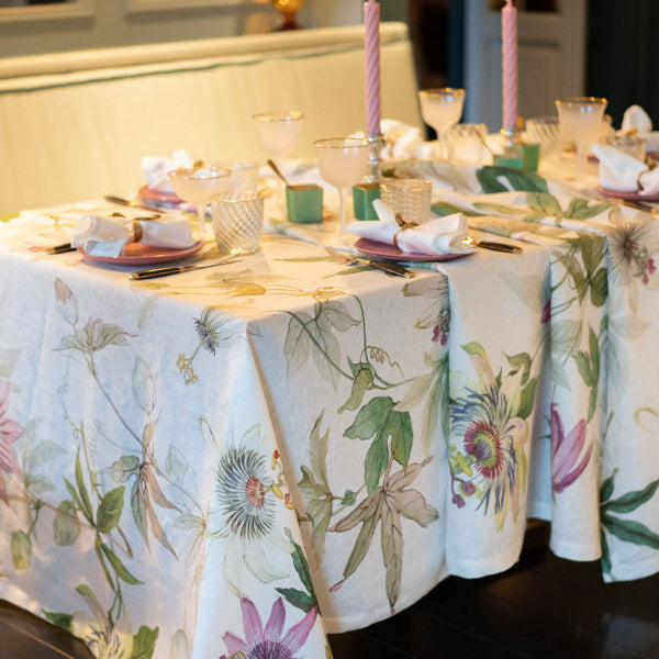 Dining table set with floral tablecloth and pink candles in a home setting.
