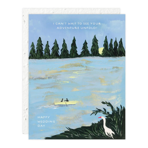 A wedding greeting card featuring a painted lakeside scene with pine trees, a small rowboat, and a white bird in the foreground. White text on the card reads, 'I CAN'T WAIT TO SEE YOUR ADVENTURE UNFOLD!' and 'HAPPY WEDDING DAY.