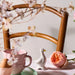 Decorative setting with a teacup, ceramic duck, and pink flower on a wooden surface.