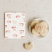 A flat-lay of a white greeting card with a Santa Claus pattern and a plate of sugar cookies on a textured light gray surface.