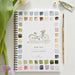 Spring watercolor workbook with a bicycle illustration and color swatches, surrounded by art supplies on a white surface.