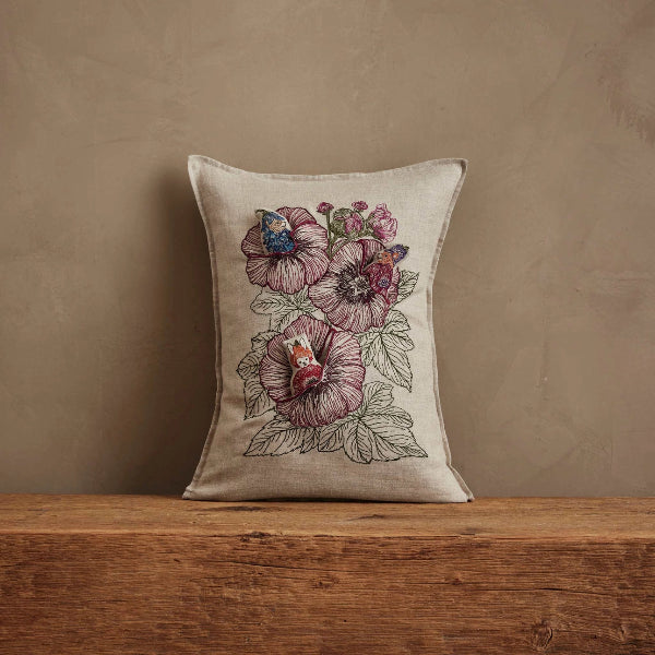 Decorative pillow with floral embroidery on a wooden surface and beige background