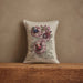 Decorative pillow with floral embroidery on a wooden surface and beige background
