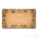 Wooden cutting board with engraved floral patterns on a white background