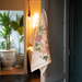 Floral-patterned towel hanging on a door with a blurred indoor background