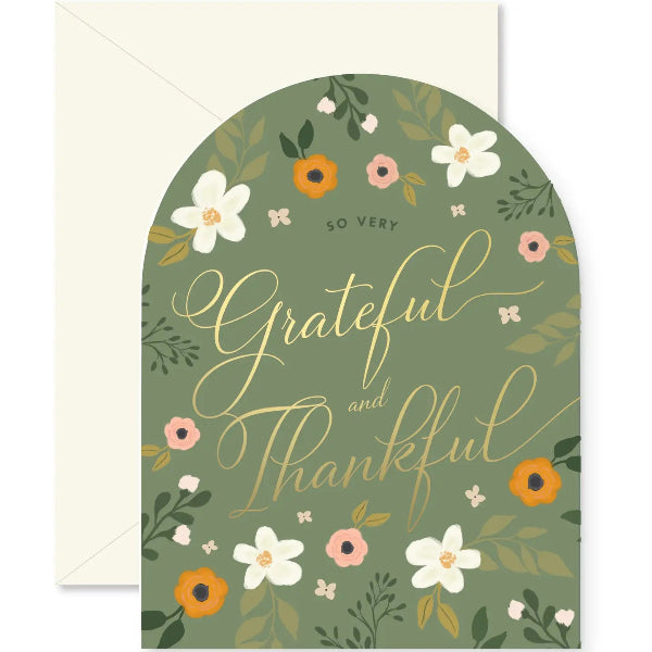 An arched floral greeting card with the words 'So very Grateful and Thankful' in gold script, shown with a cream envelope behind it. The card has an olive green background with white, pink, and orange flowers and green leaves.