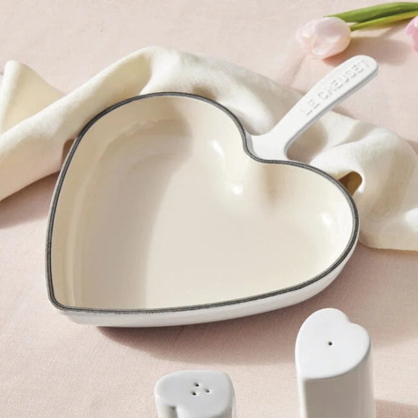 Heart-shaped ceramic dish with a handle on a soft pink background