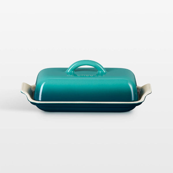 Teal ceramic butter dish with a lid on a white background