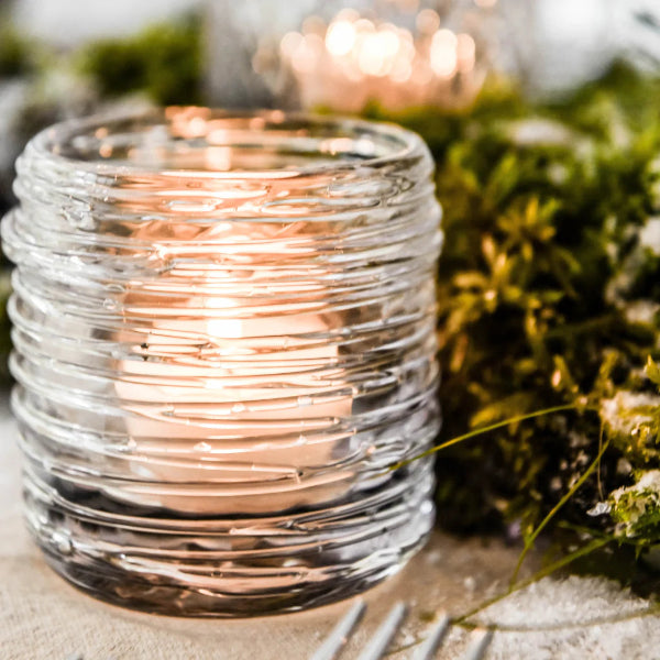 Clear glass candle holder with string lights on a natural background