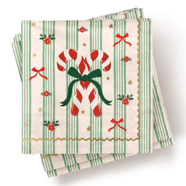 A stack of square paper napkins with a festive Christmas design, featuring green and white vertical stripes, red candy canes tied with a green bow, red bows, gold stars, and holly accents on a cream background.