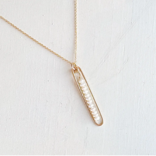 Gold necklace with a bar-shaped pendant on a white background