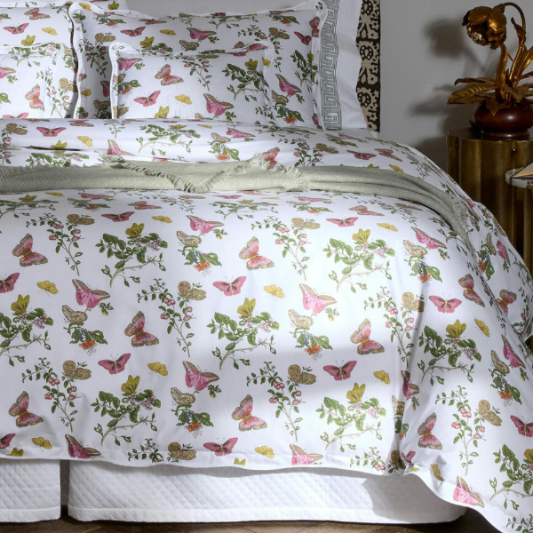 Butterfly and floral patterned bedding set on a bed with a nightstand in the background.