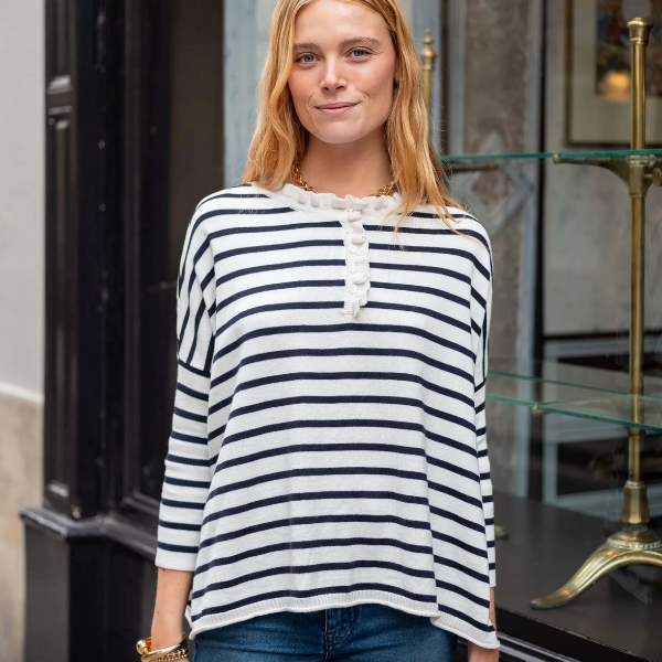 Woman wearing a black and white striped shirt standing in an indoor setting.