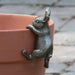 Bronze rabbit-shaped planter holder on a terracotta pot with a blurred background