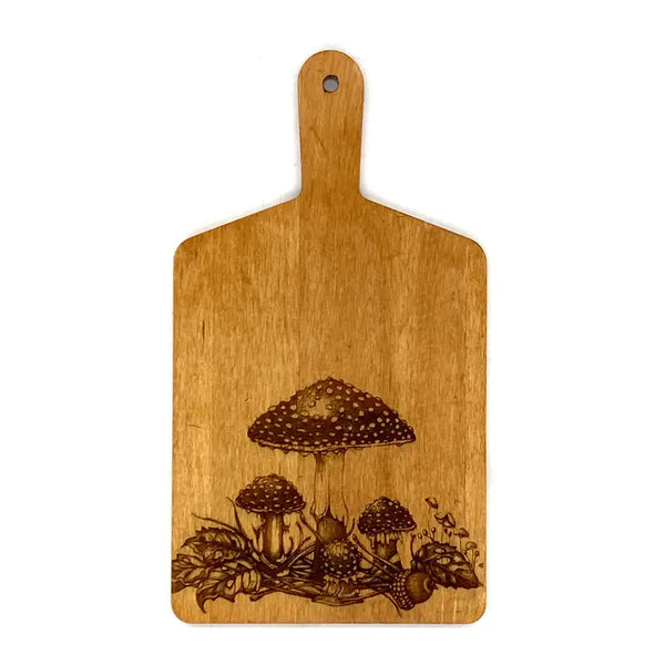 A rectangular wooden cutting board with a handle, featuring a laser-burned illustration of mushrooms and pinecones near the bottom, shown against a plain white background.