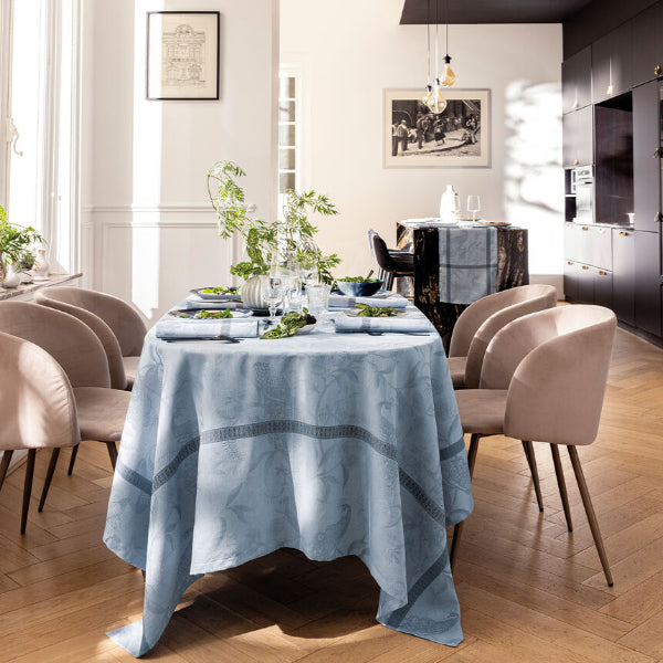 Dining room with a table set for a meal, featuring a blue patterned tablecloth and chairs.