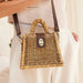 Wicker handbag with brown leather accents held by a person wearing a light-colored outfit.