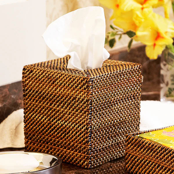 Woven tissue box cover on a marble surface with flowers in the background