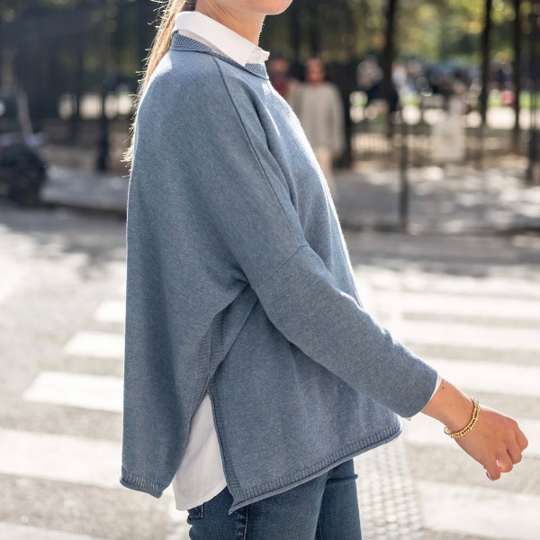 Person wearing a blue sweater and jeans on a city street