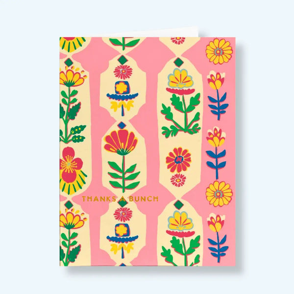 A greeting card with a colorful folk-art floral pattern on a pink and cream background, featuring the text 'THANKS A BUNCH' in gold near the bottom, shown on a light blue background.