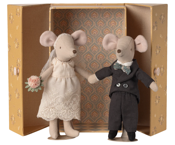 Two toy mice, one in a wedding dress and the other in a suit, standing in front of an ornate box.