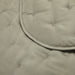 Close-up of a kaki tufted fabric surface with a curved stitched border and small tufted details.